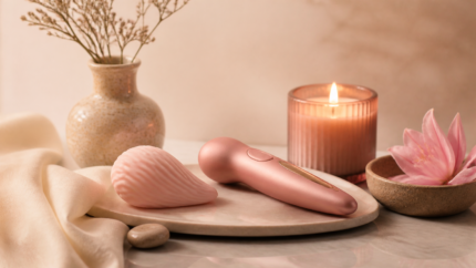 Accesorios íntimos rosas junto a una vela sobre una mesa de spa