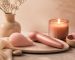 Accesorios íntimos rosas junto a una vela sobre una mesa de spa